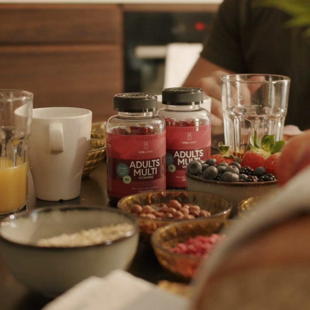 Vitamini za imunitetbVitaYummy Adults ,ulti dvije bočice okružene posudama zdravih grickalica